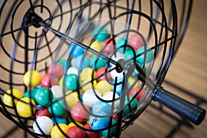 Multi-colored bingo balls in cage sitting on a desk.