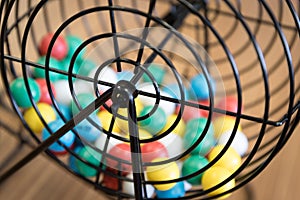 Multi-colored bingo balls in cage sitting on a desk.