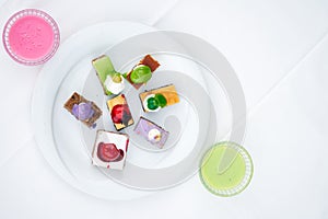 Multi-colored biscuit cakes on a white plate with berry mousse in glasses. Celebration, breakfast, baby food. Top view