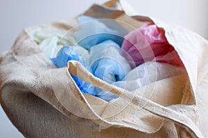 Multi-colored blue, red, white plastic bags in a rag cotton bag