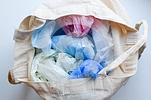 Multi-colored blue, red, white plastic bags in a rag cotton bag