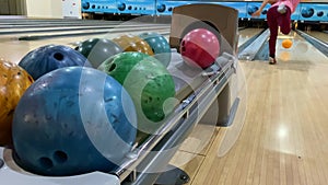 Multi-colored bowling balls close-up. Woman throws a bowling ball.