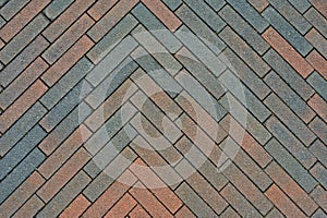 Multi-colored brick pavement, herringbone pattern, on a sidewalk.