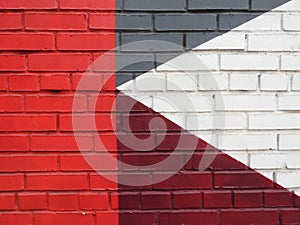 A multi-colored brick wall with red, white and gray triangles on it.