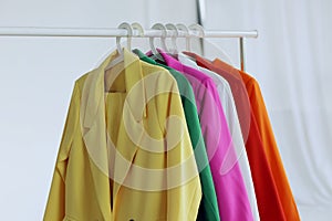 Multi-colored bright jackets on a hanger on a white background