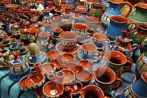 Multi-colored ceramic mugs on counter of the store. Antique dishes. Reconstruction of medieval dishes. Painting on ceramics