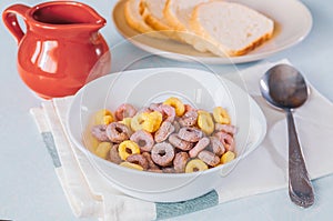 Multi-colored cereal rings in a white plate and red milkman