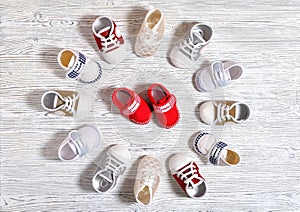 multi-colored children`s shoes on a white-gray non-uniform wooden background