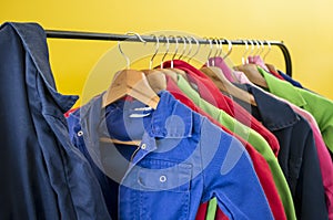Multi-colored children`s workwear for creative work hangs on hangers, against the backdrop of a bright yellow wall, in a kids clu