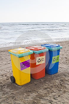 multi-colored containers for sorting garbage are on the beach ag