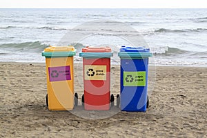 multi-colored containers for sorting garbage are on the beach ag