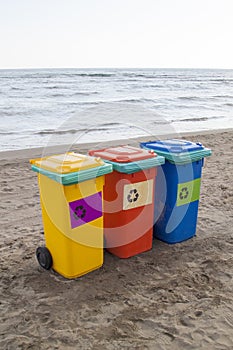 multi-colored containers for sorting garbage are on the beach ag