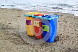 multi-colored containers for sorting garbage are on the beach ag