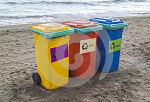 multi-colored containers for sorting garbage are on the beach ag