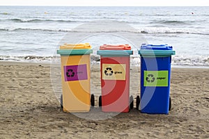 multi-colored containers for sorting garbage are on the beach ag