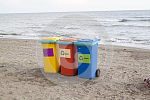 multi-colored containers for sorting garbage are on the beach ag