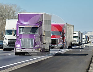 Multi-colored Convoy of Big Trucks Rolls Down The Interstate