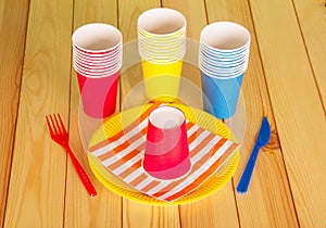 Multi-colored disposable cups on the background light wood