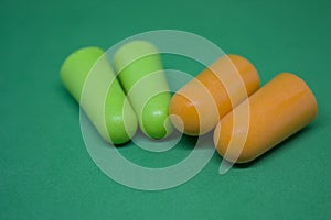 Multi-colored ear plugs on a green background. Close-up. Selective focus