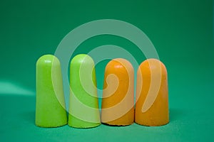 Multi-colored ear plugs on a green background. Close-up. Selective focus