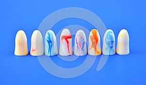 multi-colored earplugs stand in row on a blue background