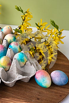 multi-colored Easter eggs on a wooden background, a green background next to yellow flowers