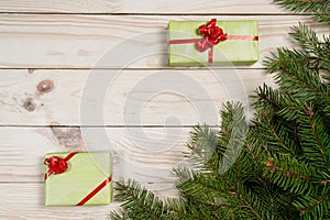 Multi-colored gift boxes and spruce branches on a wooden background.