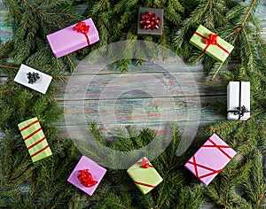 Multi-colored gift boxes and spruce branches on a wooden background