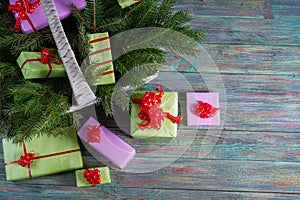 Multi-colored gift boxes and spruce branches on a wooden background