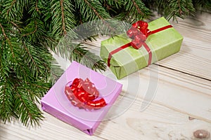 Multi-colored gift boxes and spruce branches on a wooden background