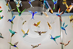 Multi-colored glass birds hang on strings.