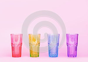 Multi-colored glasses for drinks on a pink background. Minimastic composition. Glasses of glass