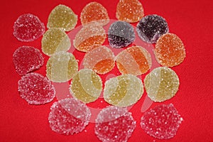 Multi-colored jelly candies on a red background. Cookies with an orange ball isolated on red. Jelly group
