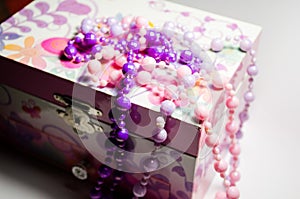 Multi-colored jewelry with beads on a pink casket. Casket for jewelry. Jewelry made of beads. This is a jewelry box. Jewelry