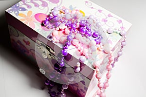 Multi-colored jewelry with beads on a pink casket. Casket for jewelry. Jewelry made of beads. This is a jewelry box. Jewelry