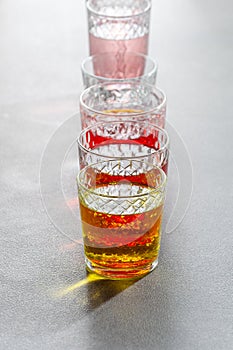 Multi-colored lemonades in glass faceted glasses on a yellow gray table