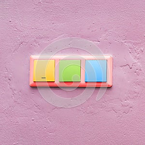 Multi-colored light switches on a pink wall. Fashionable colorful electrical switch. Creative style. Concept art