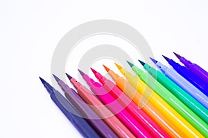 Multi-colored markers with a brush tip, arranged according to the colors of the rainbow. White background. The concept of