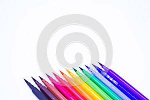 Multi-colored markers with a brush tip, arranged according to the colors of the rainbow. White background. The concept of