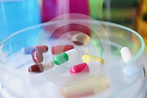 Multi-colored medical pills lie on glass test tube closeup