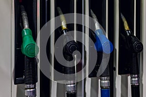 Multi colored nozzles of fuel pumps with hoses at a gas station close up. Background