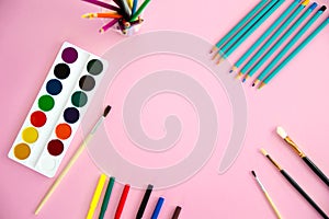 Multi-colored objects for drawing and creativity for children lie on a pink background. Bright watercolor paints, pencils, brushes