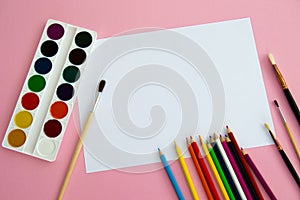 Multi-colored objects for drawing and creativity for children lie on a pink background. Bright watercolor paints, pencils, brushes