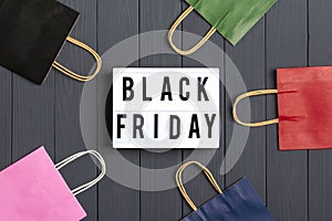 Multi colored packaging bags, gift boxes lightbox with text Black Friday on dark gray