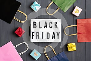 Multi colored packaging bags, gift boxes lightbox with text Black Friday on dark gray