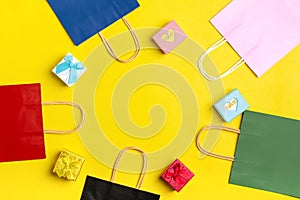 Multi-colored packaging bags, gift boxes  on  yellow background Top view