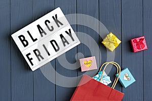 Multi colored packaging bags, trolley, sprig of eucalyptus, cup of coffee gift boxes lightbox with text Black Friday on  dark gray