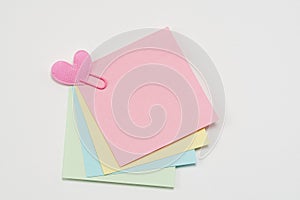 Multi-colored paper notes fastened with a paper clip on a white background