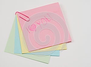 Multi-colored paper notes fastened with a paper clip on a white background. With the inscription I love you
