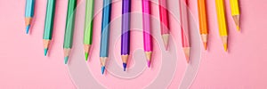 Multi-colored pencils close-up pastel banner pink background